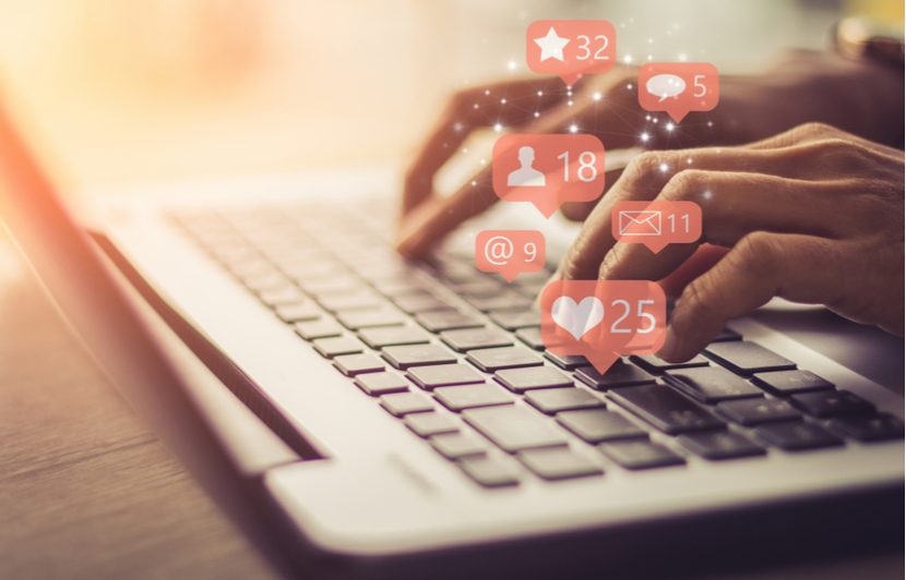hands typing on a laptop with social media notifications