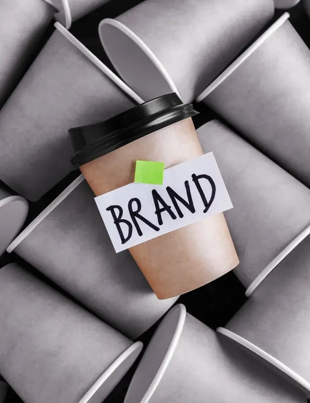 Stylized image of a coffee cup labeled "brand" standing out from gray coffee cups, representing branding trends