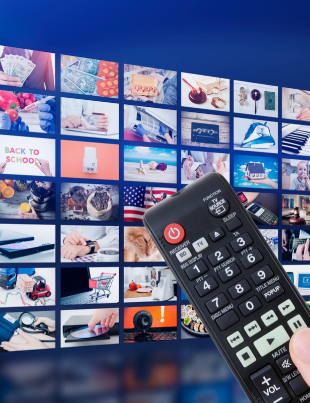 Image of a remote in front of a wall of screens showing various media