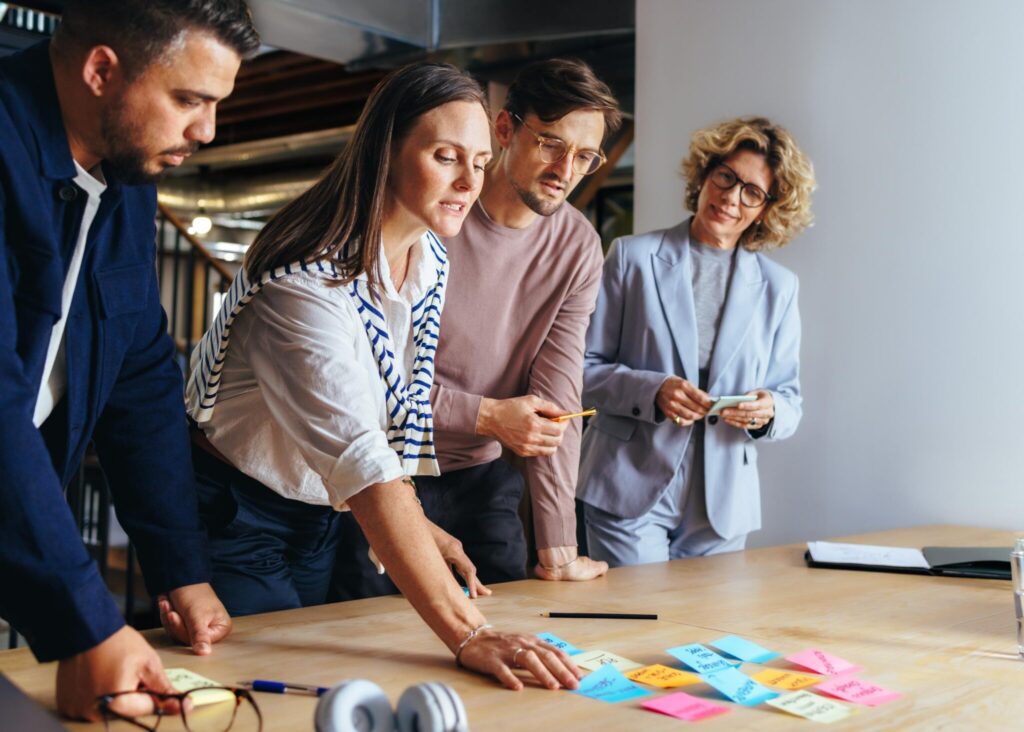 Marketing team brainstorming with sticky notes in an office. Business professionals discussing ideas in a meeting. Business people collaborating on a project in an advertising agency.