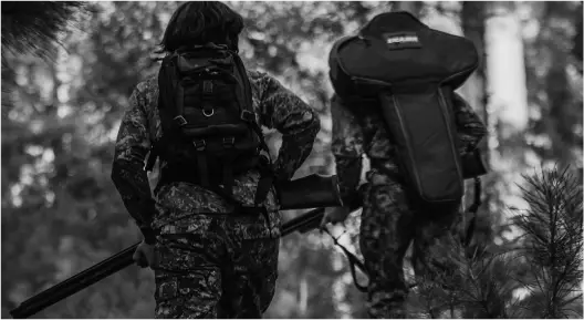 two armed officers walking through a forest
